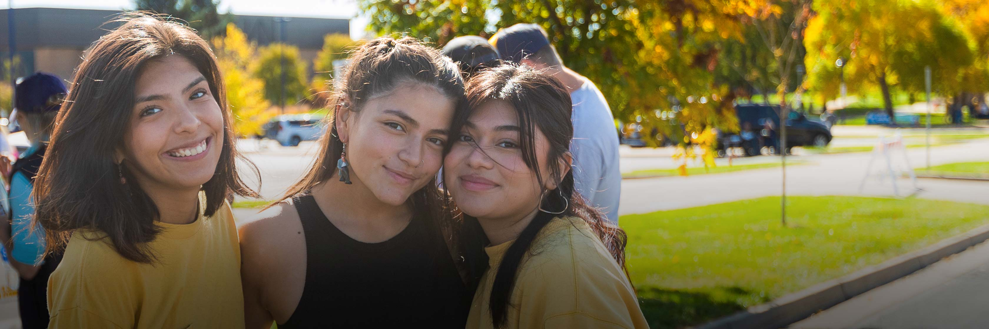 3 latina students smiling during an event.